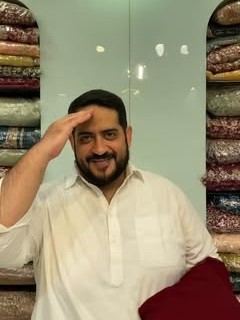 Ateeb Khan holding a maroon outfit in the store